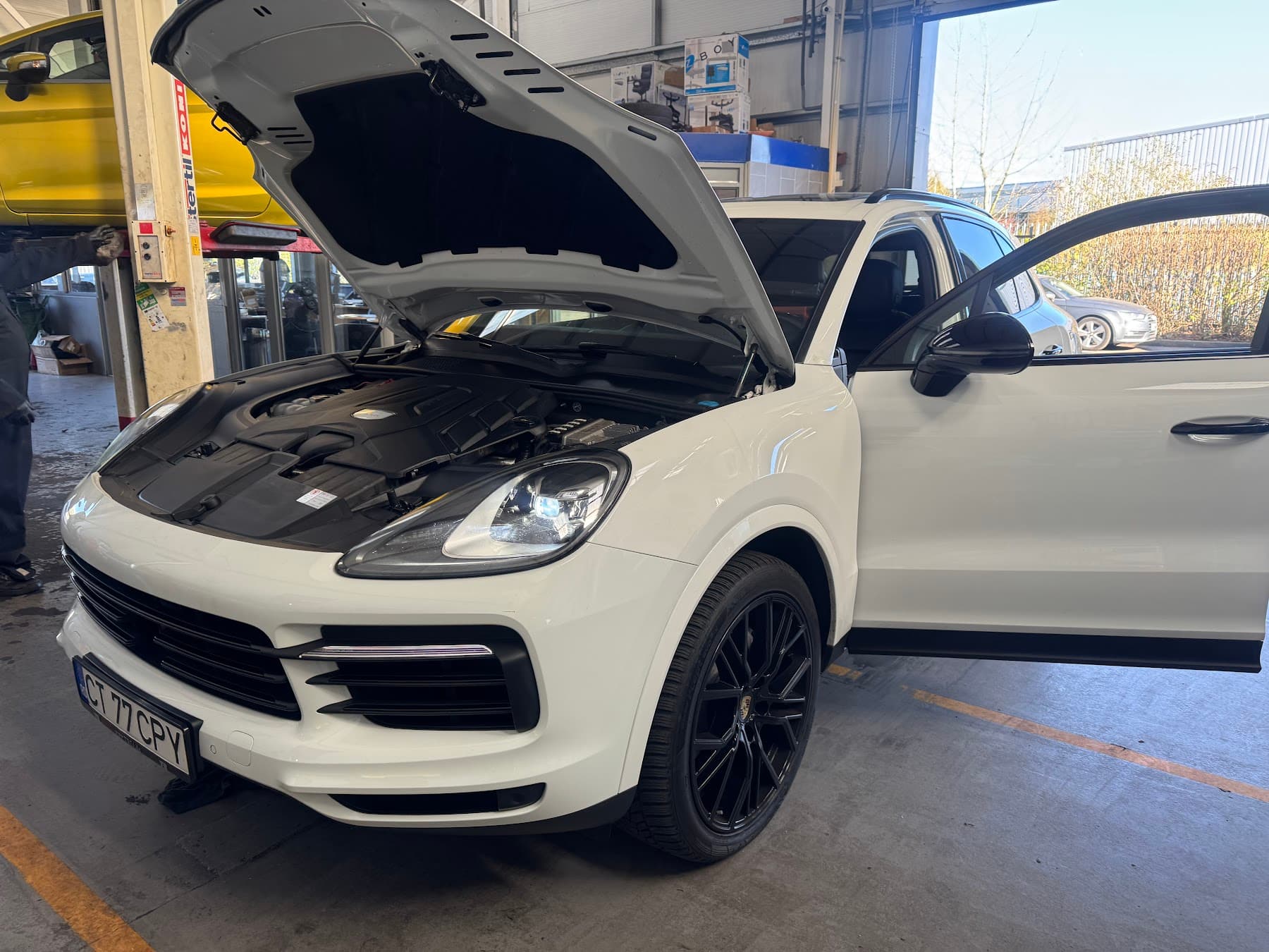 White vehicle with bonnet open inside Saki's Auto Centre workshop