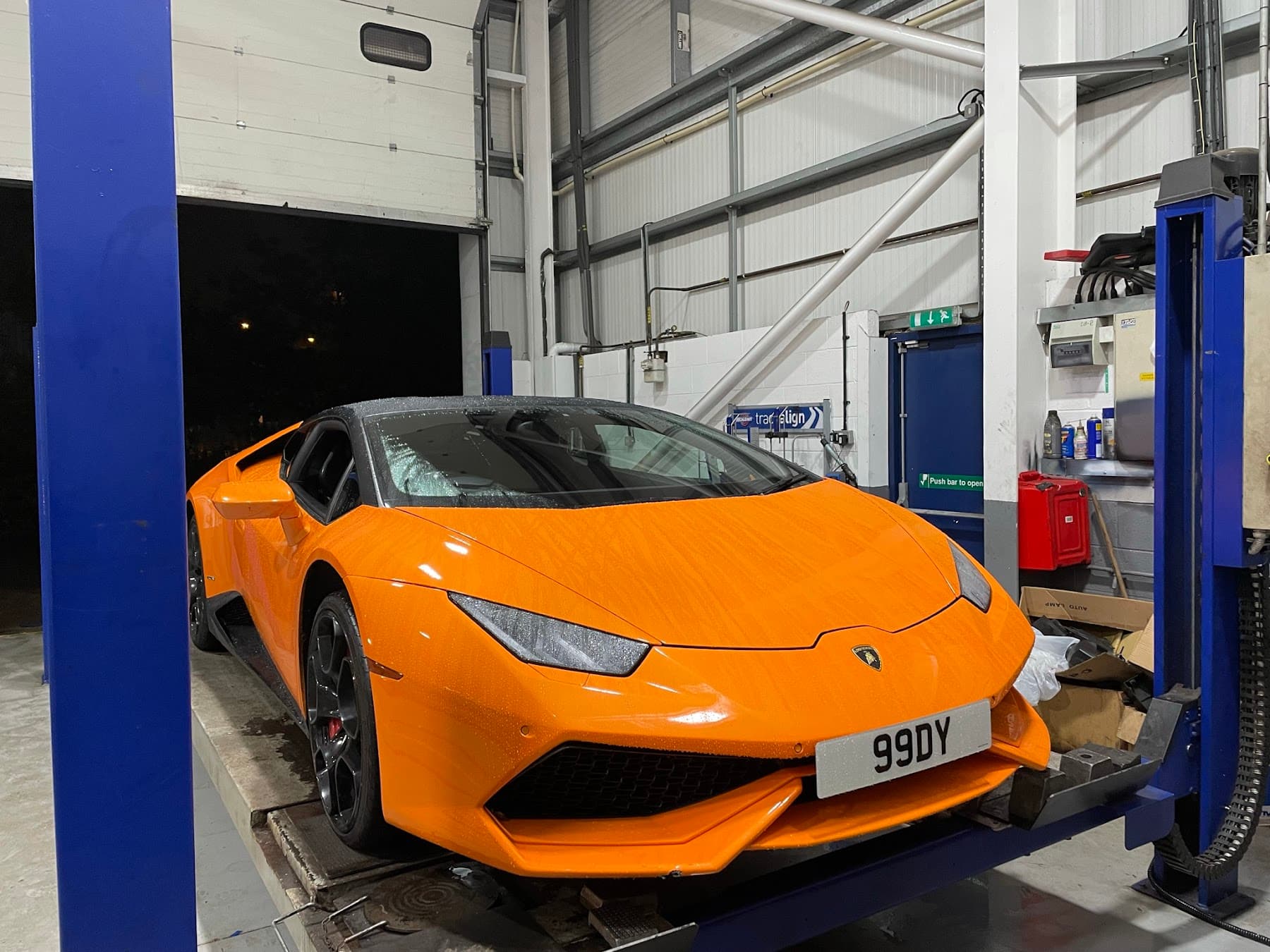 Orange sports car on a workshop ramp at Saki's Auto Centre