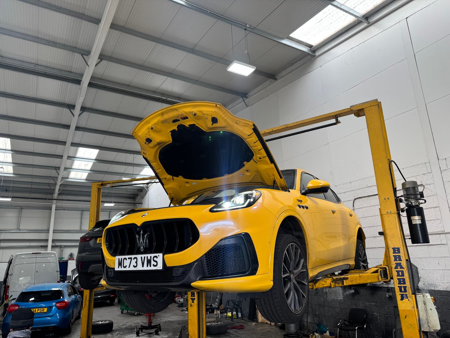 Yellow vehicle raised on a workshop ramp at Saki's Auto Centre